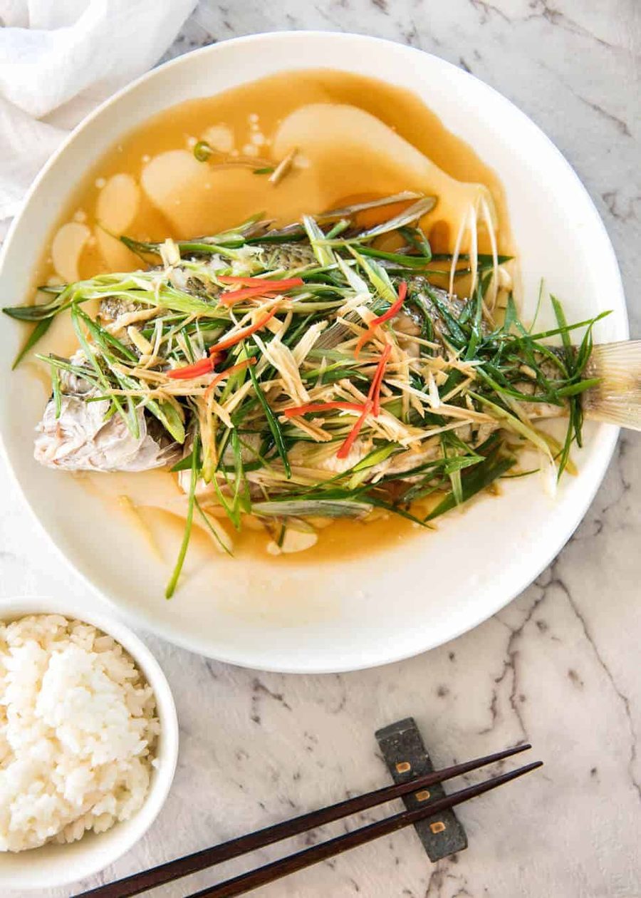 Un pescado al vapor chino amueblado con jengibre y chalotes y condimentos, con aceite caliente vertido para crear un chisporroteo espectacular y una salsa increíble. Tan simple, pero tan delicioso. ¡Vapor o hornee el pescado! Repenetineats.com