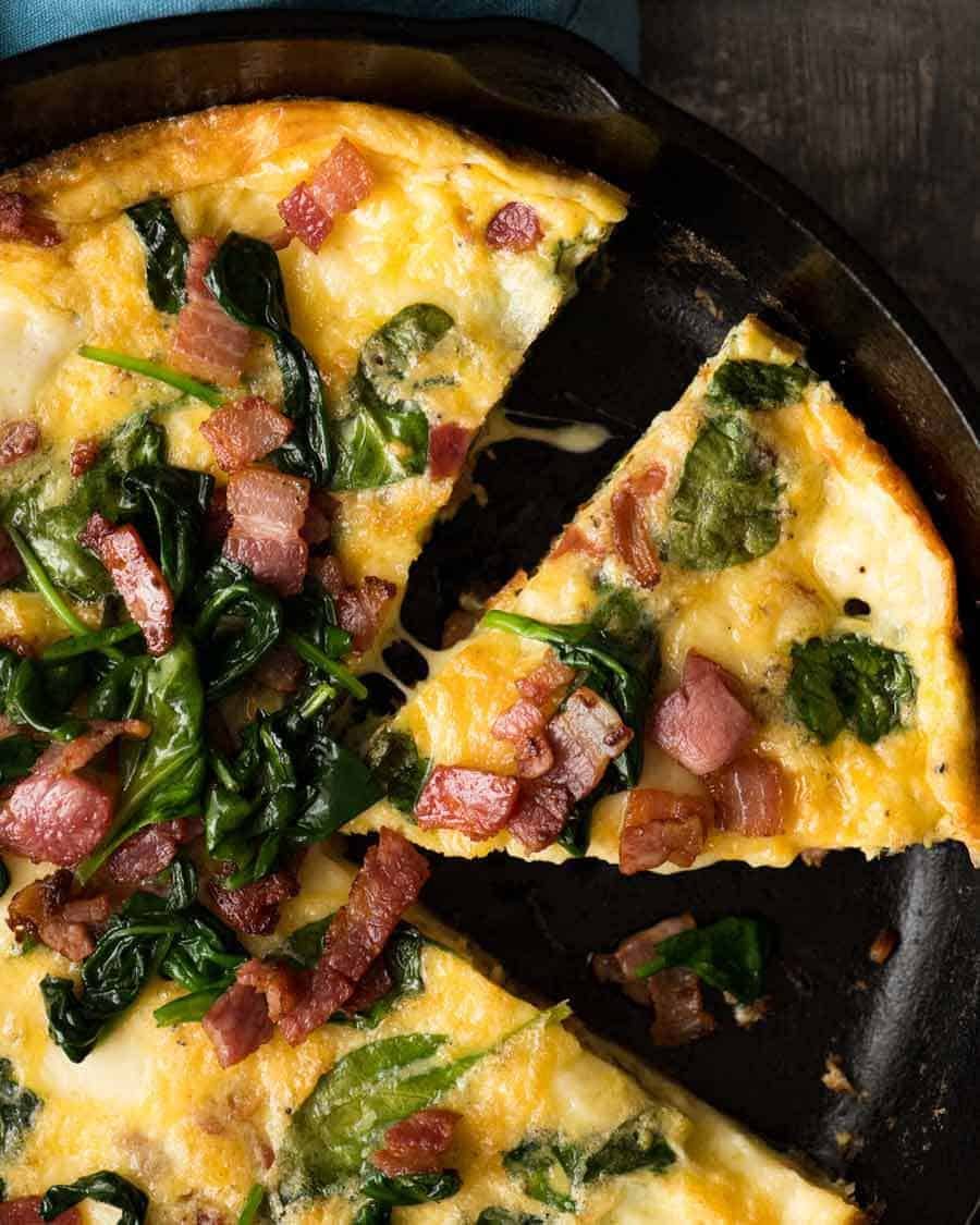 Foto aérea de Frittata con tocino y espinacas en una sartén negra, recién salido del horno