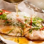 Pouring hot oil over sizzling ginger steamed fish