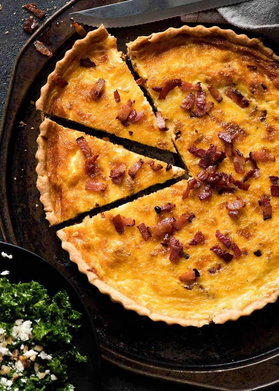 Fotografía aérea de una Quiche Lorraine dorada con 2 trozos cortados