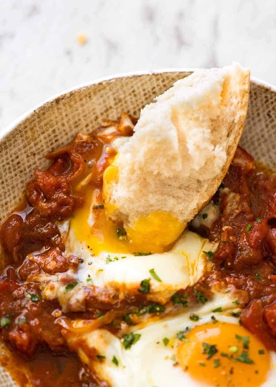 Pan empapado en yemas de flujo de Shakshuka, huevos horneados en el Medio Oriente