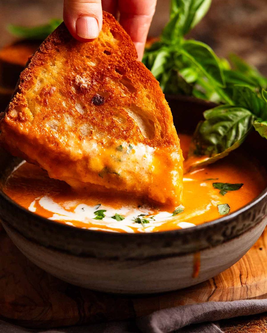 Dunnking queso a la parrilla en una sopa de tomate asado