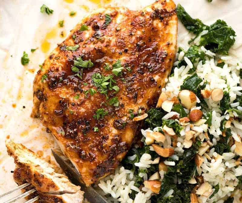 Pechuga de pollo en el horno jurado en un plato blanco con un lado de arroz con chou chou en mantequilla de ajo