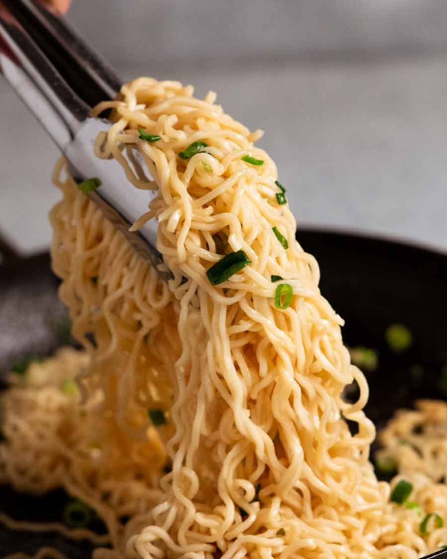 Alicates recogiendo fideos con ajo recién cocinado