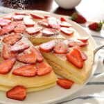 Giant pancake topped with strawberries, sprinkled with icing sugar